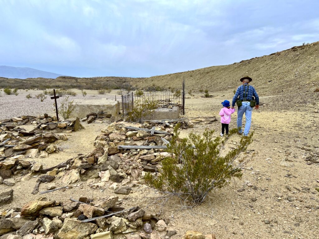 Man and small child visit a remote cemetary.